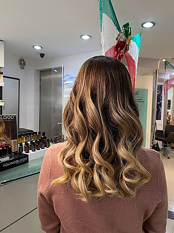 Ondas largas con balayage castaño claro, de espaldas frente al mostrador de productos