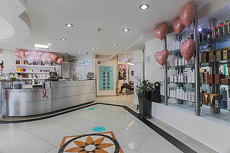 Recepción con mostrador de acero, vitrina de cristal con productos para el cabello y el mosaico del piso