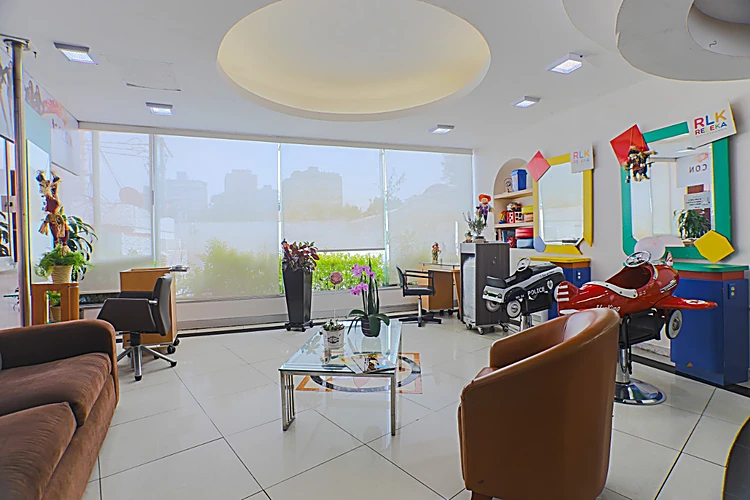 Sala de espera con sillones café, mesa de cristal y, al fondo, sillas infantiles en forma de carro