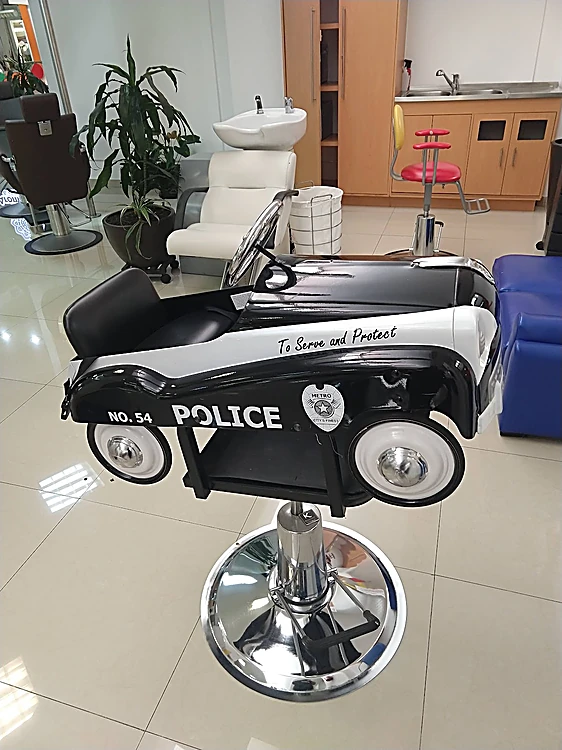 La silla infantil del salón: un carro de patrulla negro y blanco con la placa To Serve and Protect, sobre base cromada